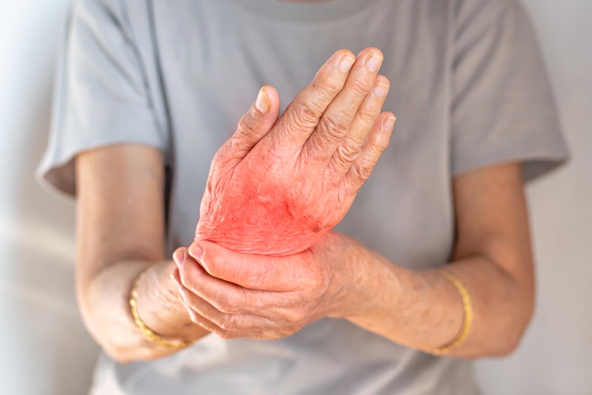 an elderly woman holds her wrist in pain